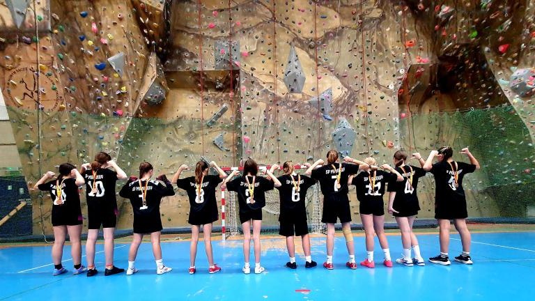 Dziewczęta odwrócone na tle ścianki wspinaczkowej.jpg