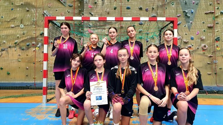 Dziewczęta z SP Maniowy z dyplomem i medalami na tle brami.jpg